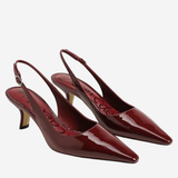 A pair of glossy burgundy patent leather slingback kitten heels with pointed toes, displayed on a light gray background.