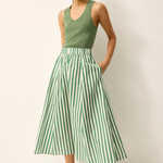 Woman wearing a green tank top and green and white striped skirt against a white background