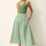 Woman wearing a green tank top and green and white striped skirt against a white background