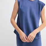 Woman wearing a blue sleeveless dress against a white background