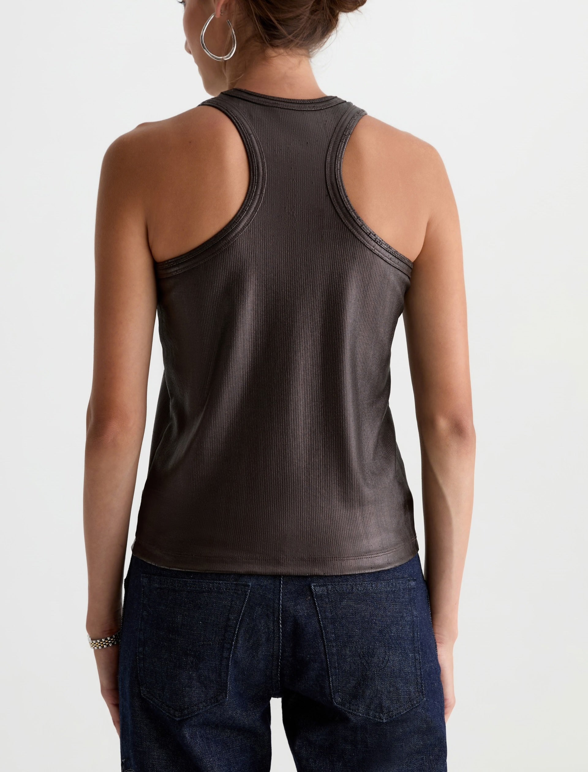 Person wearing a brown tank top and dark jeans on a white background