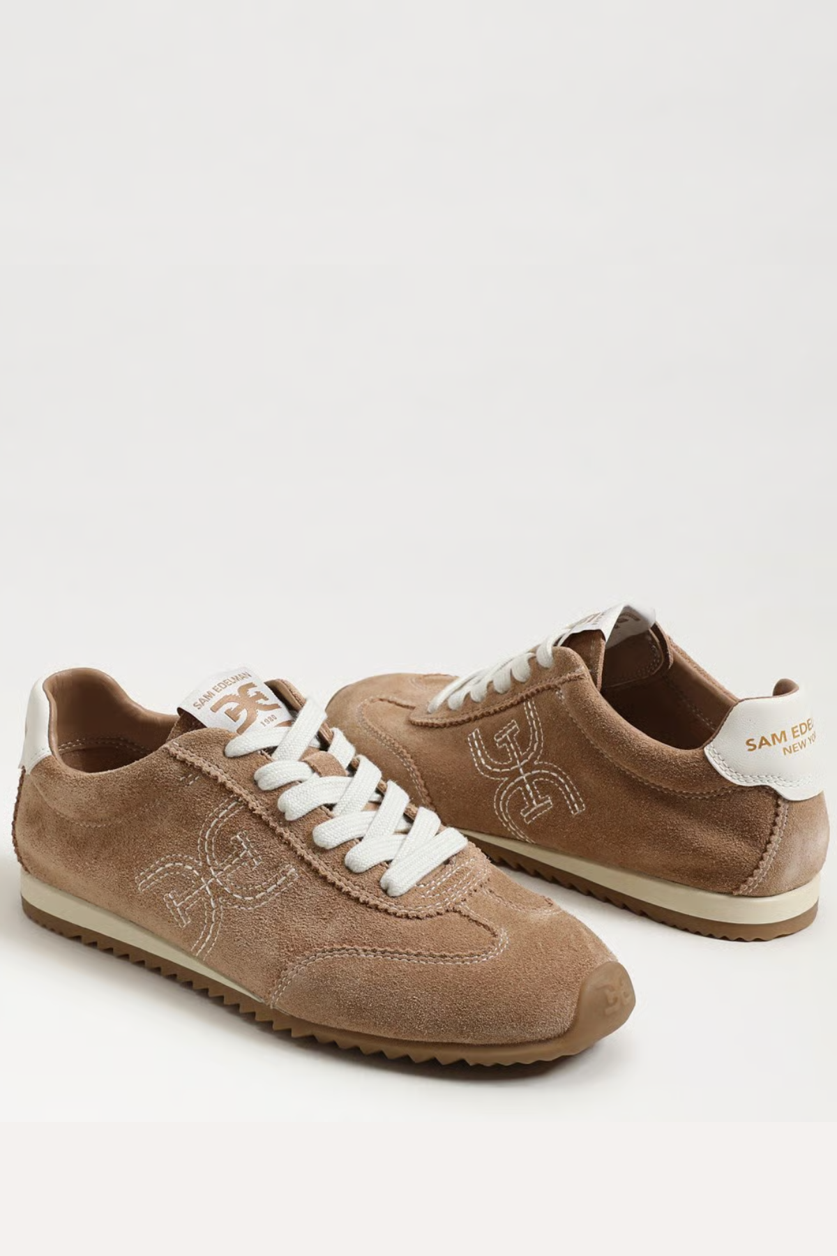 Pair of brown sneakers with white laces on a white background