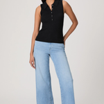 Woman wearing a black sleeveless polo shirt and light blue jeans on a white background