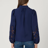 Navy blue blouse with lace sleeves back view by a person on a light gray background