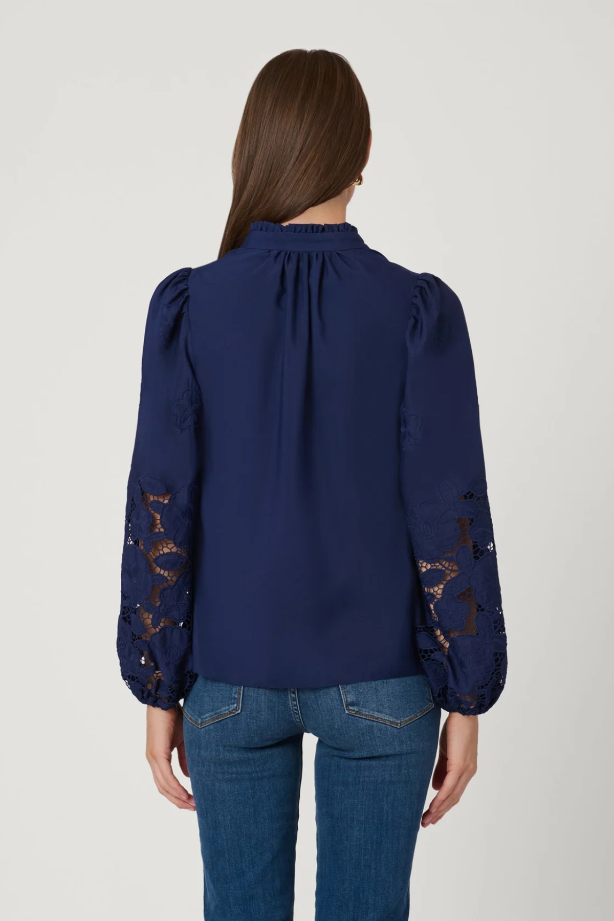 Navy blue blouse with lace sleeves back view by a person on a light gray background
