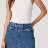 Person wearing a white tank top and blue denim skirt on a plain background
