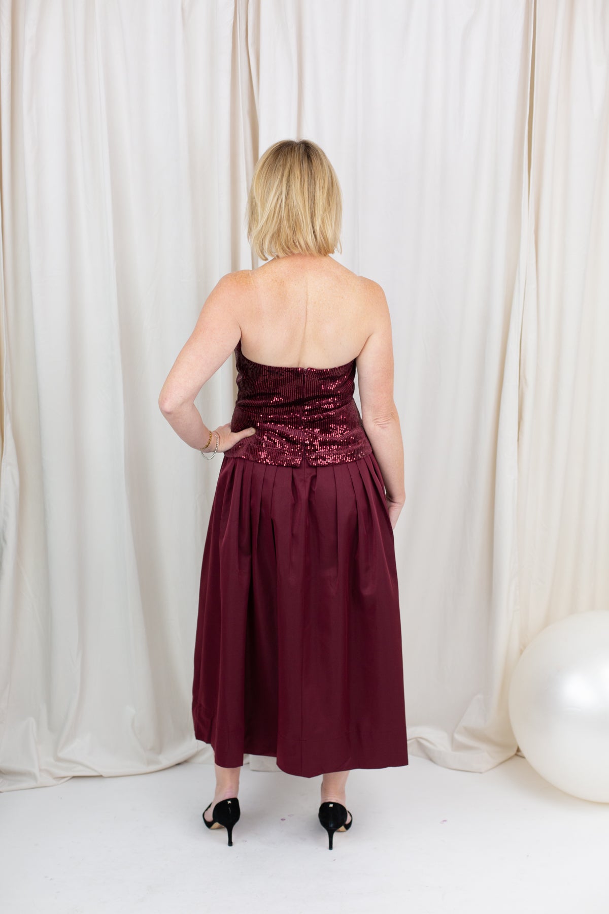 Burgundy sequin dress for evening wear paired with heels