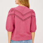 Pink blouse with lace details on a plain background