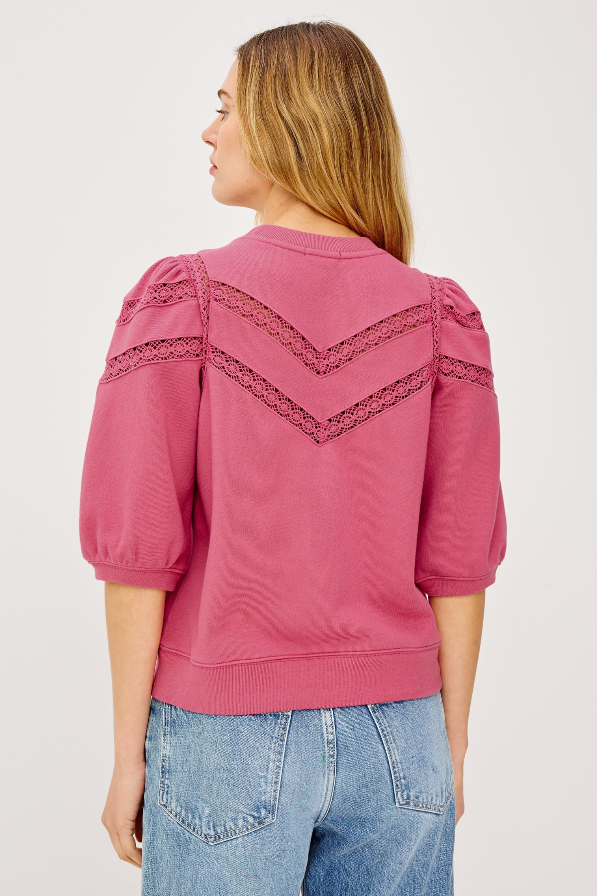Pink blouse with lace details on a plain background