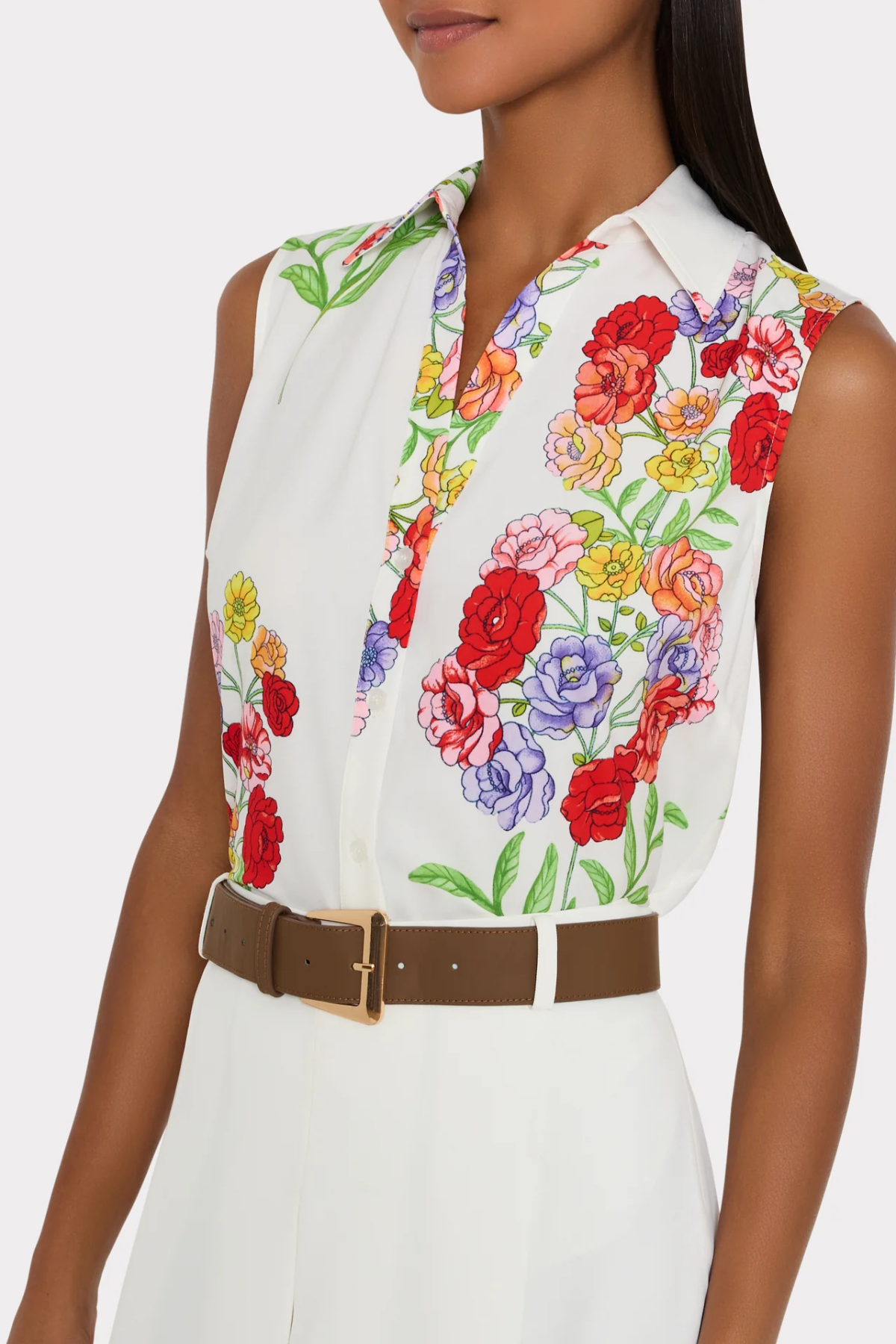 Woman wearing a sleeveless blouse with colorful floral pattern on a white background