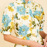 Person wearing a floral dress with blue and yellow flowers on a beige background