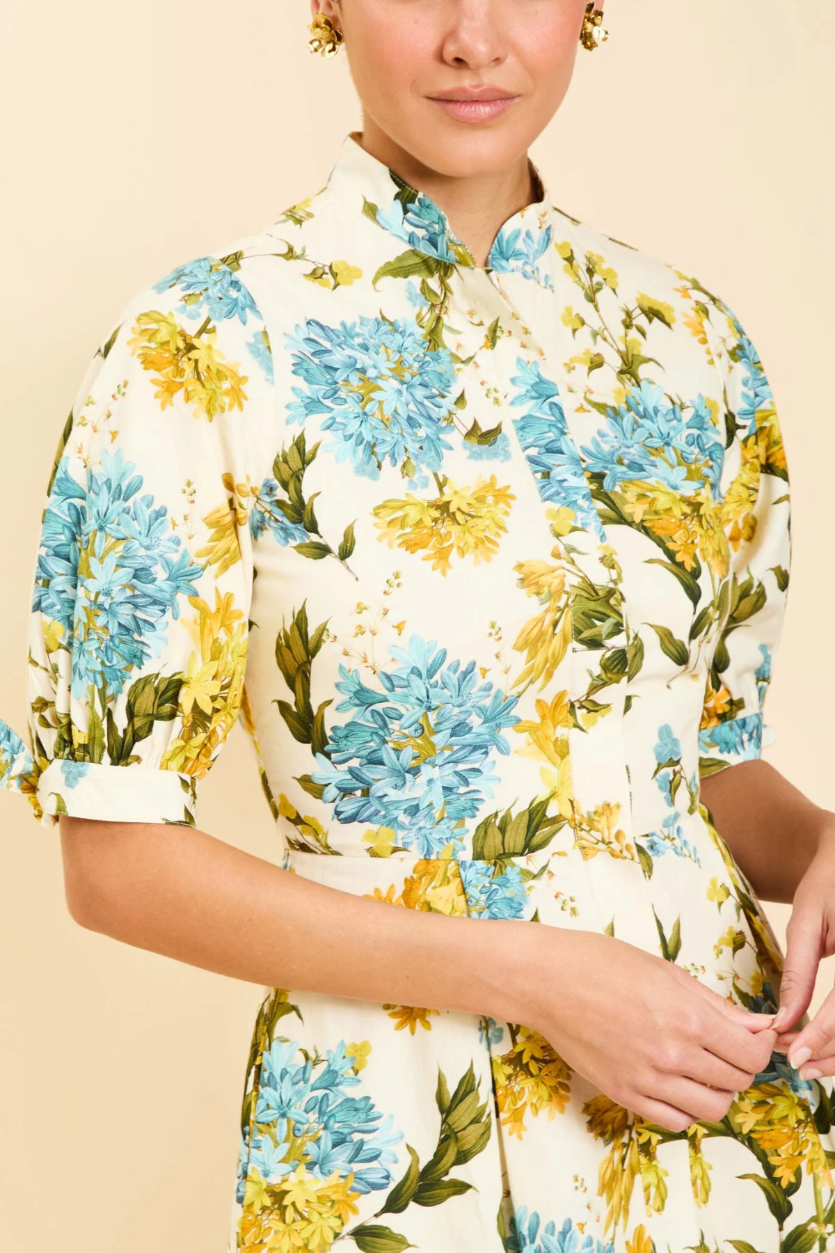 Person wearing a floral dress with blue and yellow flowers on a beige background
