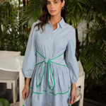 Woman wearing a light blue dress with green accents in an outdoor setting