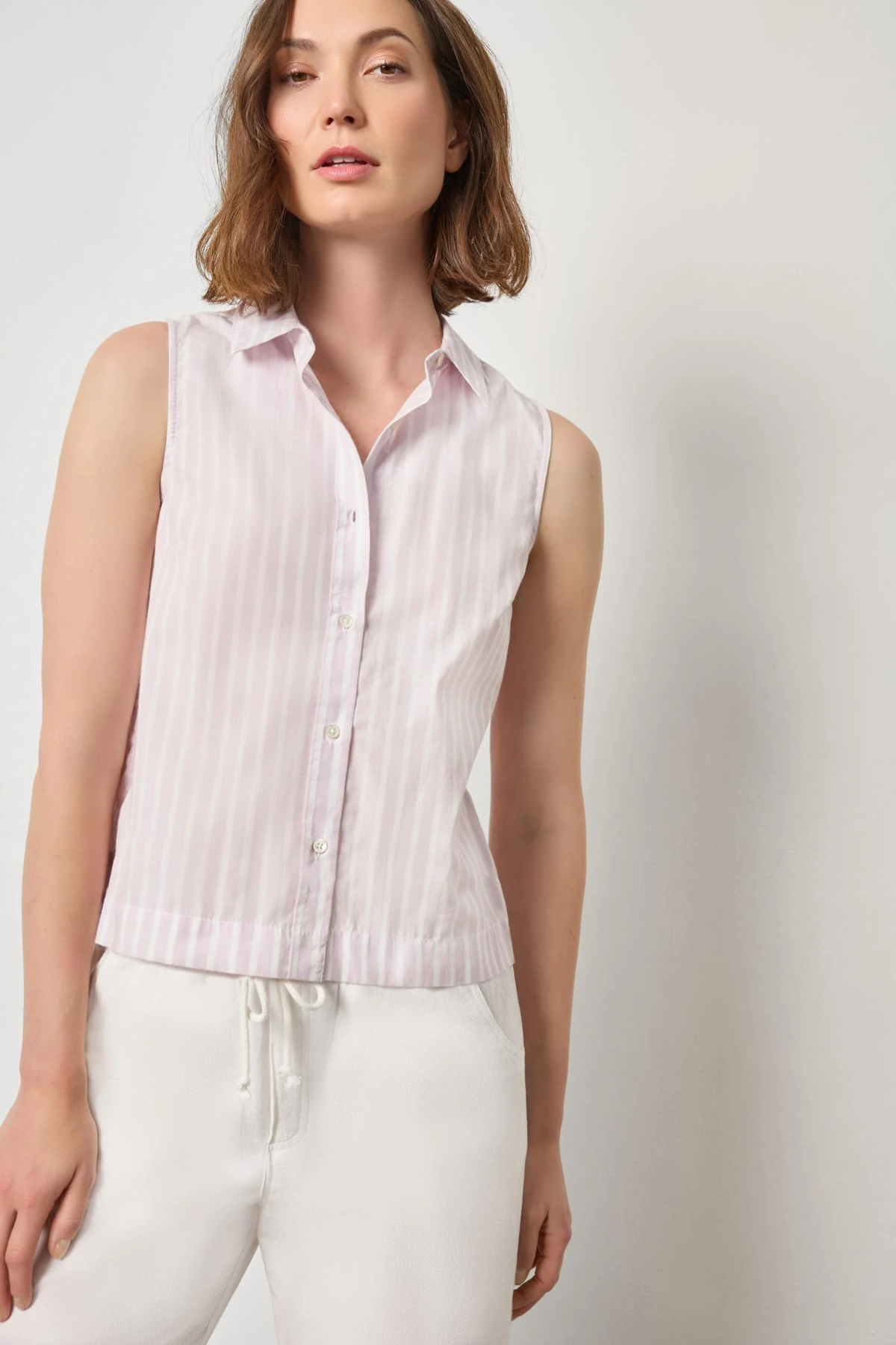 Woman wearing a sleeveless pink striped shirt against a plain background
