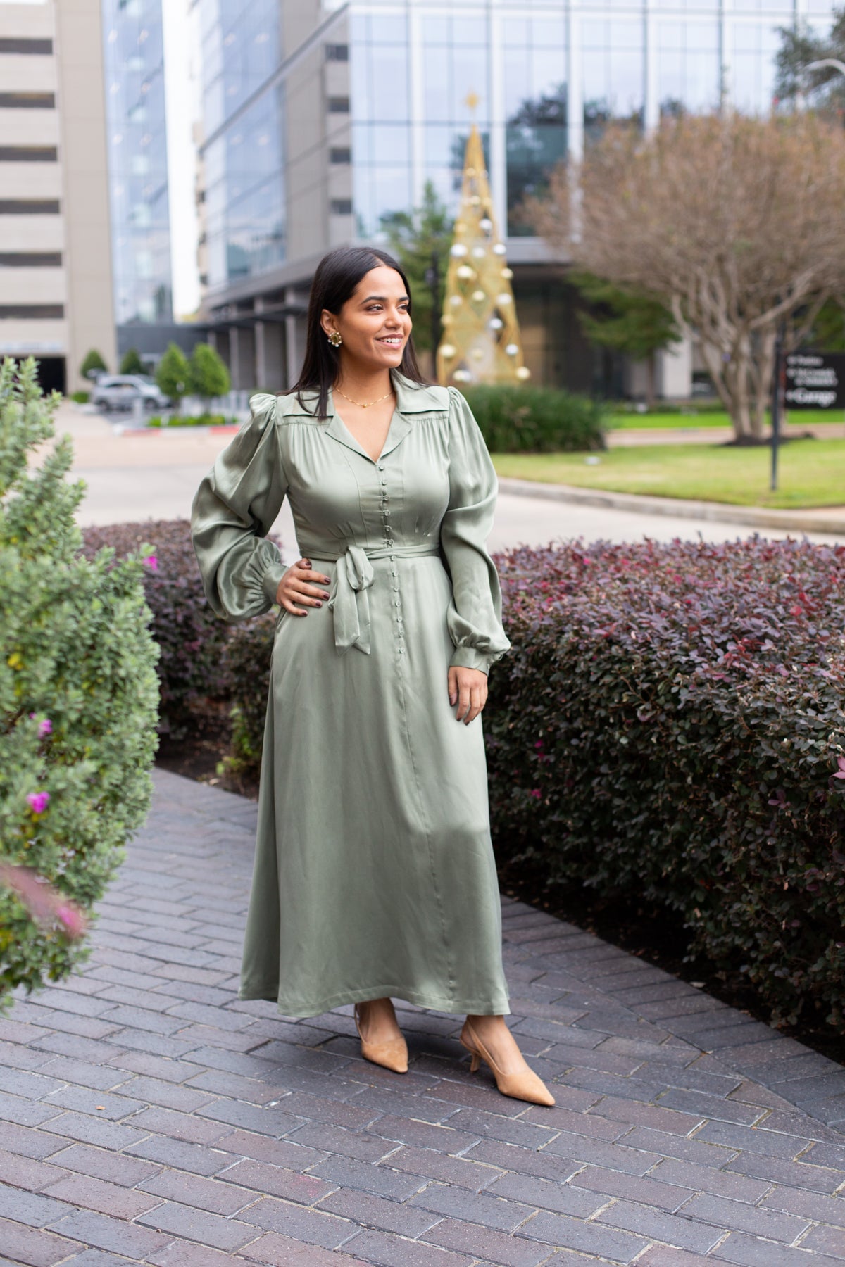Woman wearing a neutral midi dress with soft pleating and a relaxed, polished silhouette