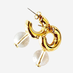 Gold-toned statement earrings featuring a polished abstract curved loop design with clear faceted round stone drops, shown on a light gray background.