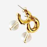 Gold-toned statement earrings featuring a polished abstract curved loop design with clear faceted round stone drops, shown on a light gray background.