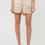 Person wearing beige tie-dye shorts on a white background
