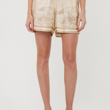 Person wearing beige tie-dye shorts on a white background
