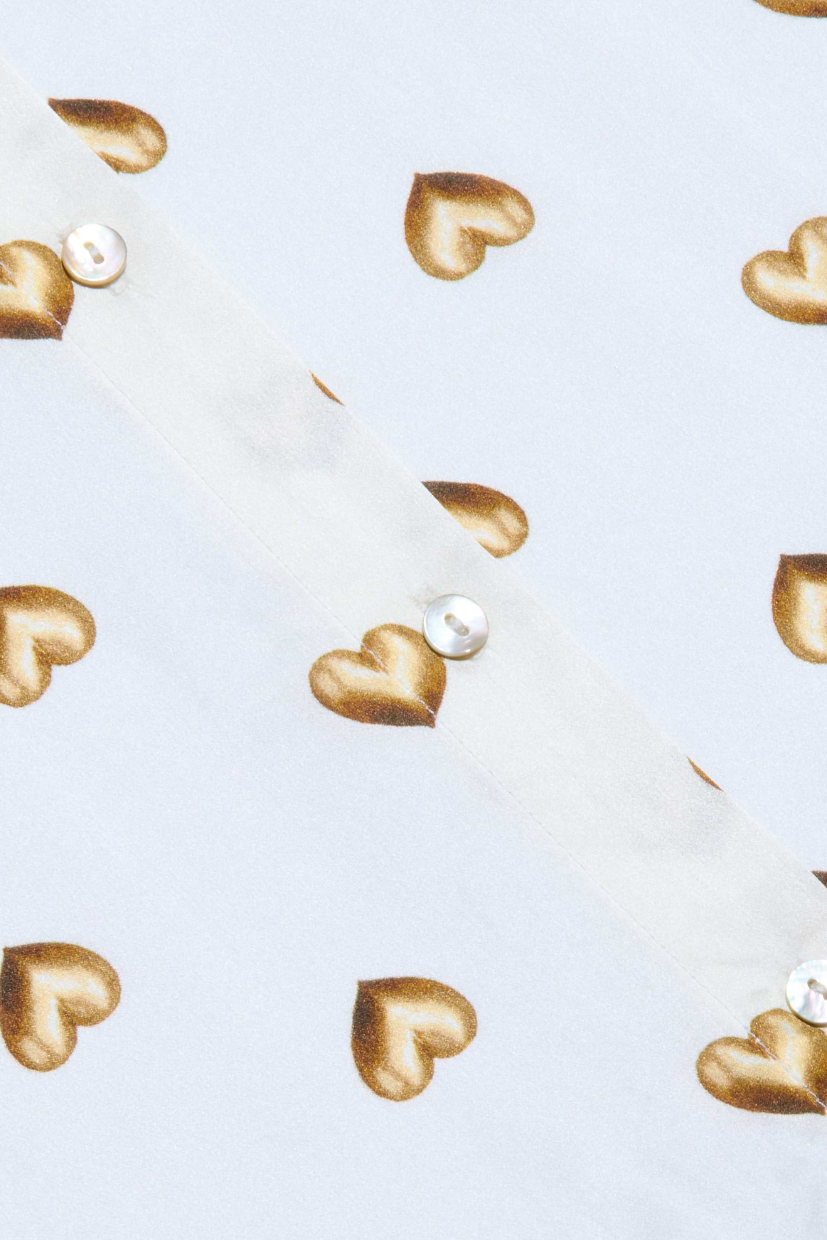 Gold heart-shaped earrings on a light blue background