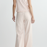 Person wearing a light pink top and wide-leg pants on a white background