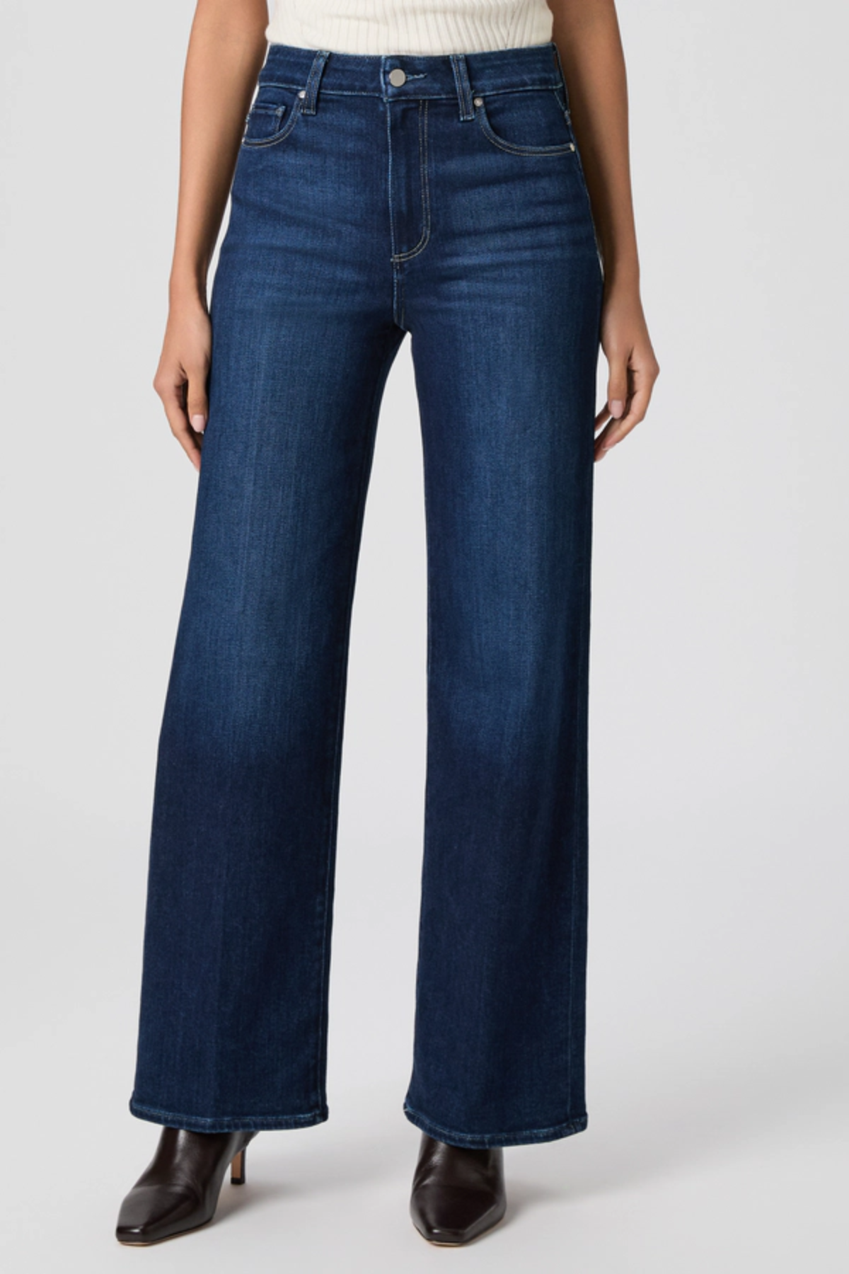 Person wearing dark blue jeans on a white background