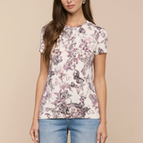 Woman wearing a floral-patterned t-shirt and jeans on a beige background