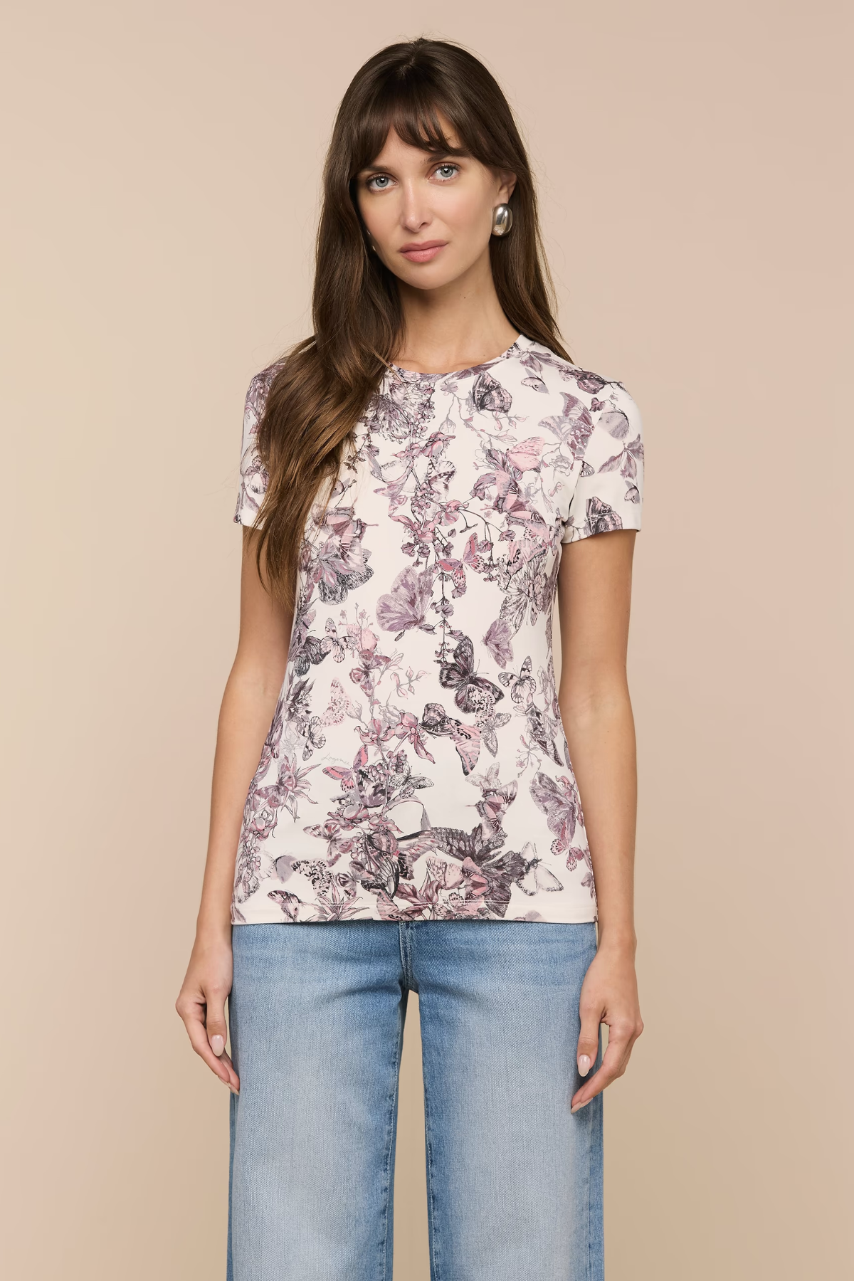 Woman wearing a floral-patterned t-shirt and jeans on a beige background