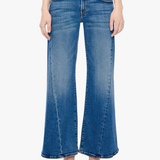 A model wearing a pair of medium-wash blue denim flare jeans with a straight-to-wide leg, paired with beige pointed-toe heels against a plain white background.
