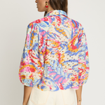 Woman wearing a colorful floral blouse with a plain background