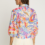Woman wearing a colorful floral blouse with a plain background