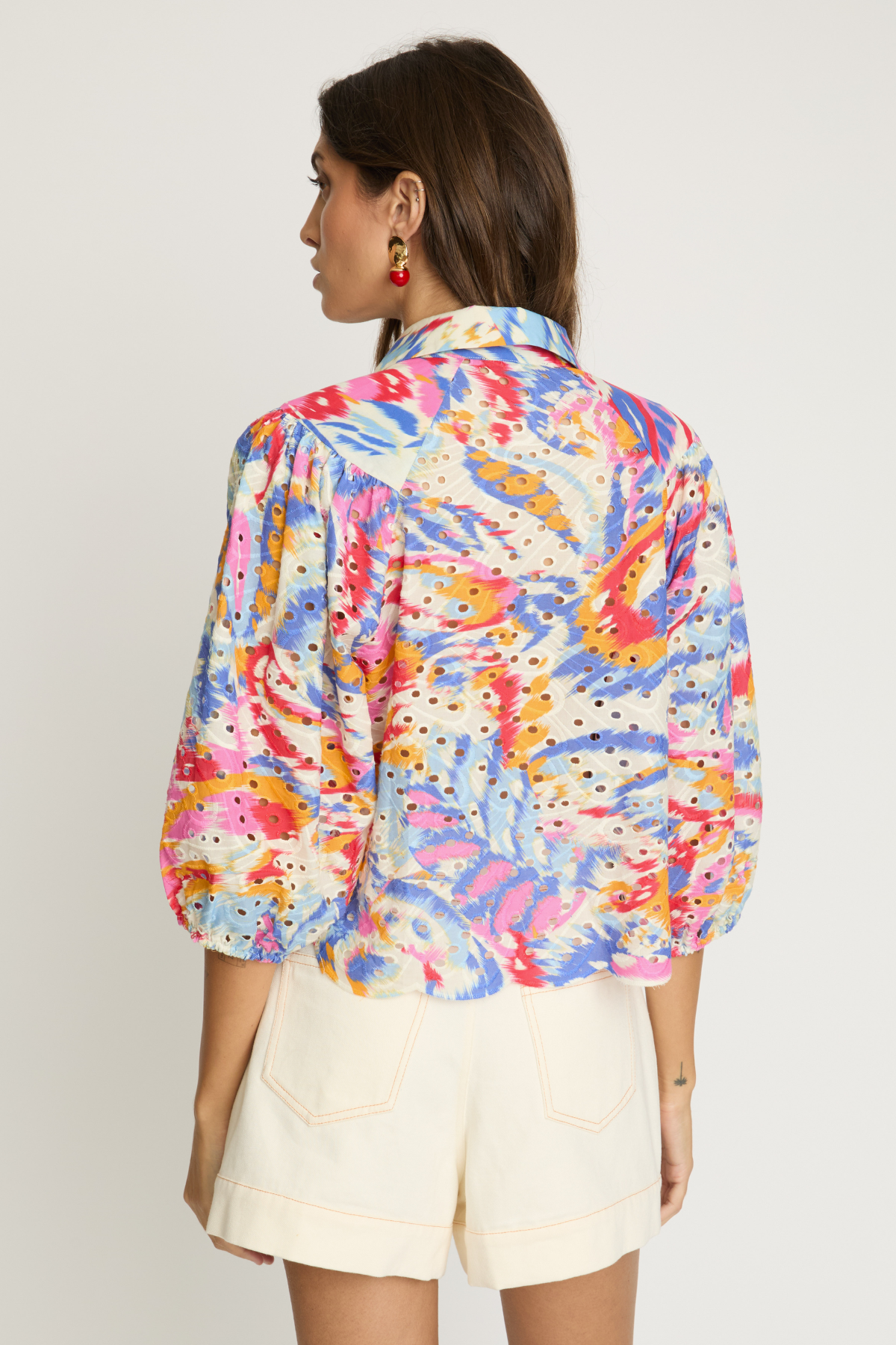 Woman wearing a colorful floral blouse with a plain background