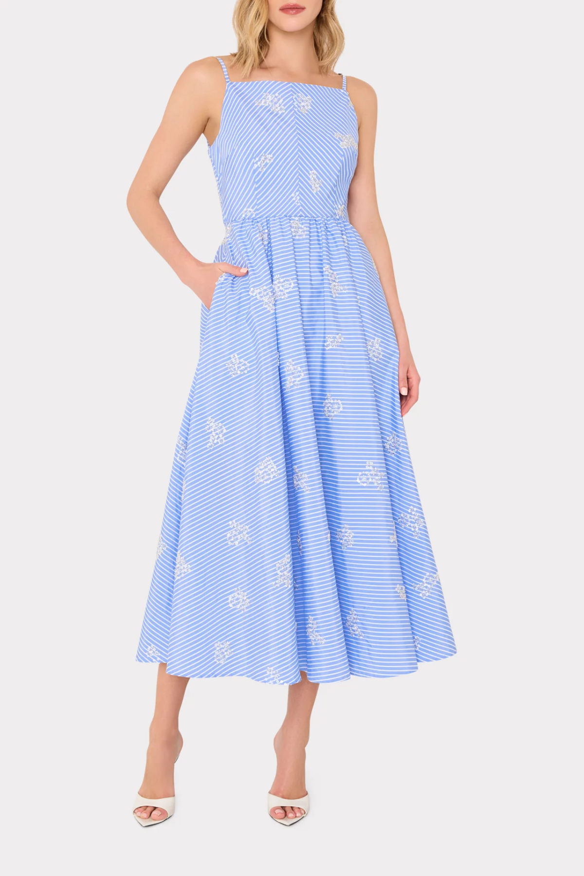 Woman wearing a blue dress with white floral patterns on a white background