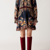 A model wearing a dark navy blue mini dress with a detailed gold, brown, and red patterned print, paired with burgundy over-the-knee boots, against a plain light gray background.