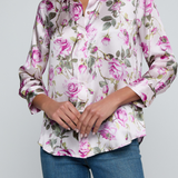 Model wearing rose print blouse with jeans on white background.