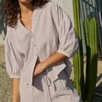 Woman wearing a striped shirt and shorts standing outdoors with a cactus in the background