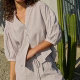 Woman wearing a striped shirt and shorts standing outdoors with a cactus in the background