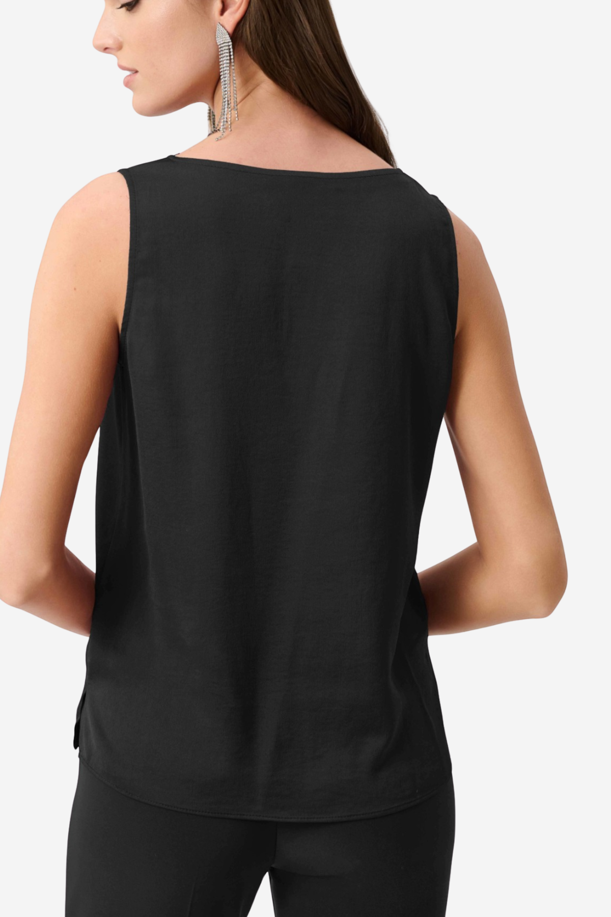 A woman shown from the back wearing a sleeveless black top and black pants against a light gray studio background.