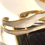 Gold bracelet on a reflective surface with a blurred background