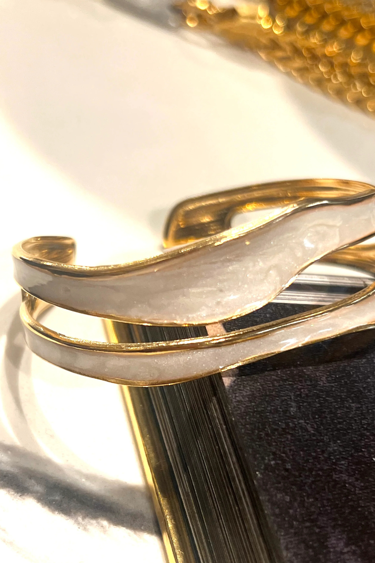 Gold bracelet on a reflective surface with a blurred background
