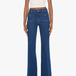 A model wearing high-waisted, wide-leg blue denim jeans with a white ribbed tank top and dark brown sandals, shown against a plain white studio background.