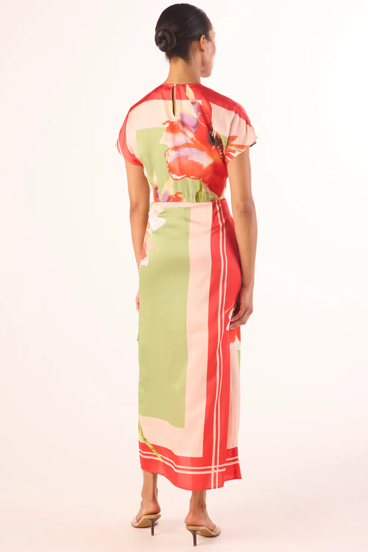Woman wearing a colorful dress with a floral pattern on a white background