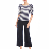 Woman wearing a black and white striped top and navy wide-leg pants on a white background