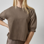 Woman wearing a brown top and skirt against a plain background