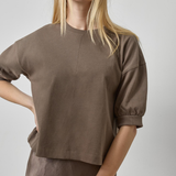 Woman wearing a brown top and skirt against a plain background