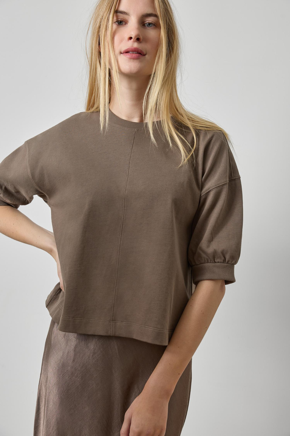 Woman wearing a brown top and skirt against a plain background