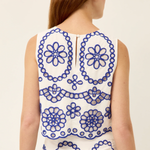 Woman wearing a sleeveless dress with blue floral patterns on a white background