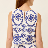 Woman wearing a sleeveless dress with blue floral patterns on a white background