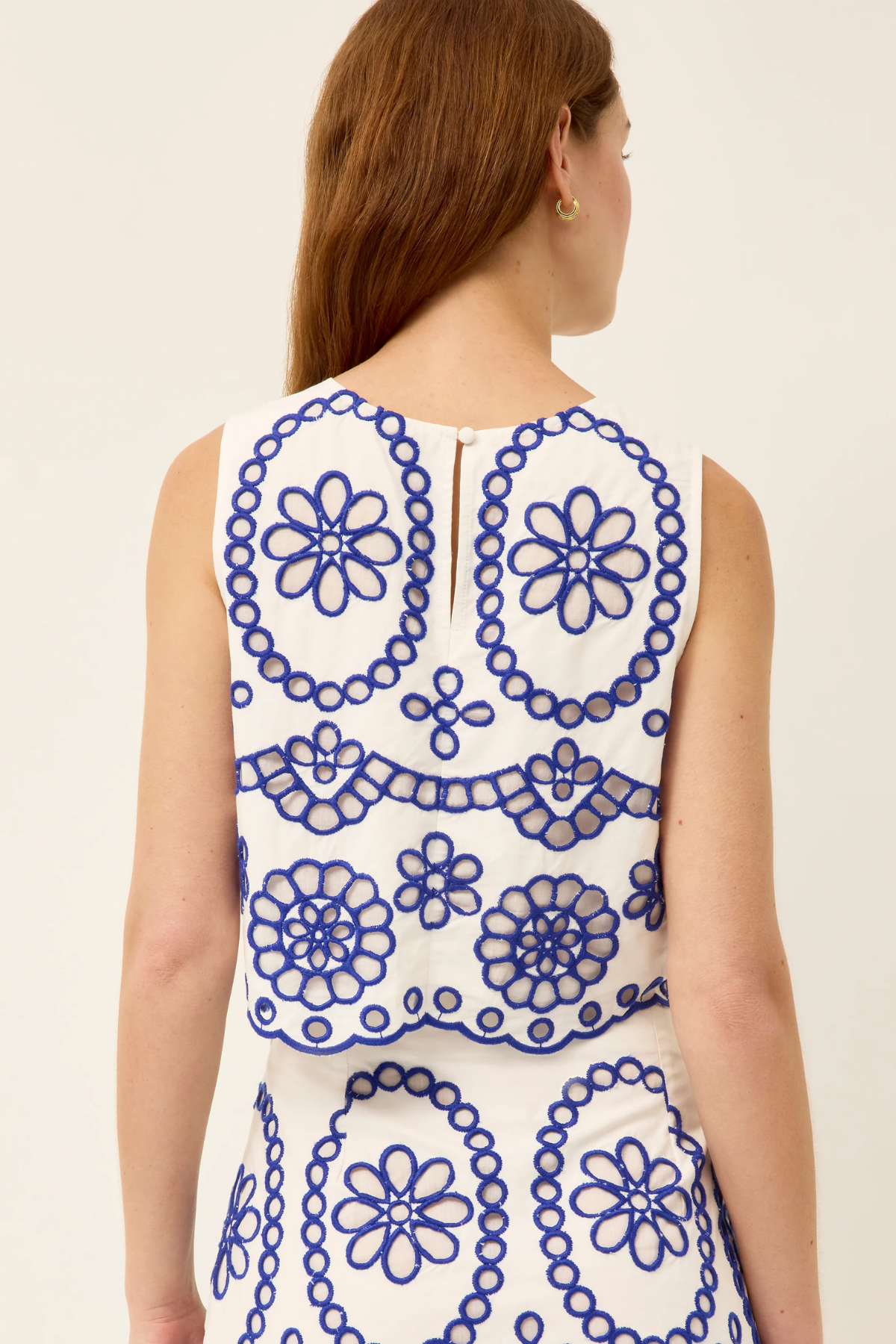 Woman wearing a sleeveless dress with blue floral patterns on a white background