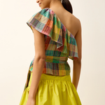 Woman wearing a colorful one-shoulder top and yellow skirt against a plain background